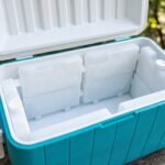 Vista interior de una hielera organizada por capas con botes refrigerantes y bebidas frías.
